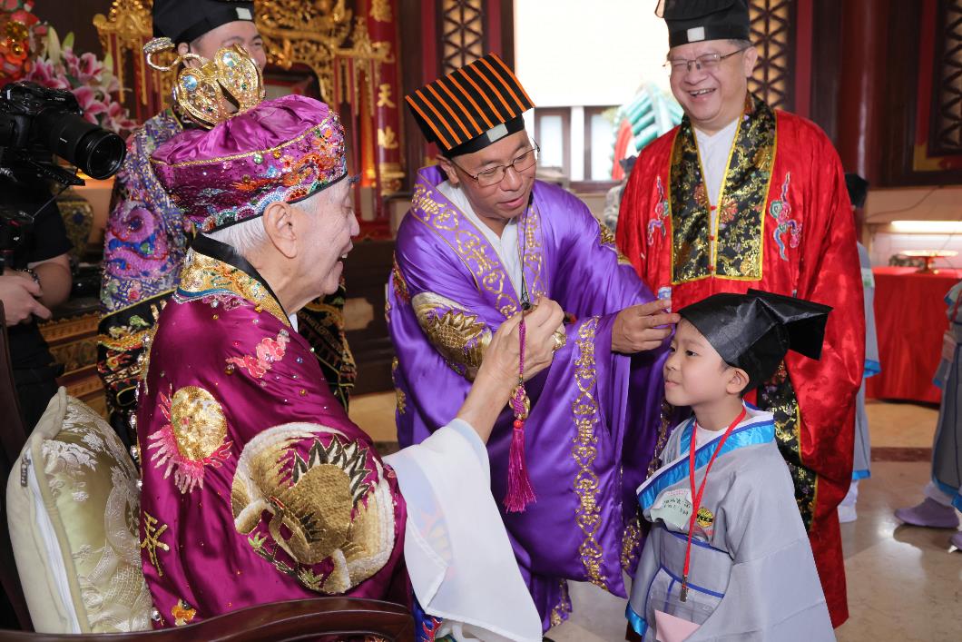 圖八：李耀輝監院於麟閣內為學子以硃砂點痣於額上，寓意為孩童開啟智慧。